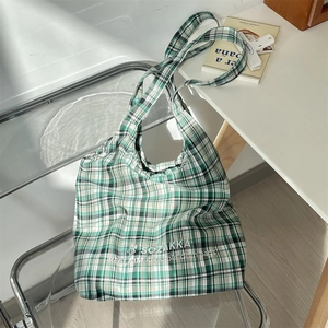 Detail of green and white checkered canvas tote bag featuring eco-friendly embroidery