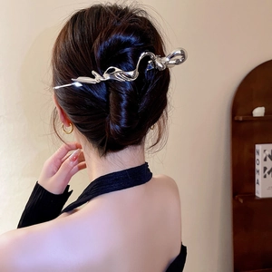 Detail view of silver liquid metal hair clip on model's sleek black bun hairstyle