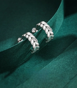 Macro shot of S925 sterling silver leaf stud earrings with clear zircon on green velvet