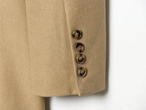 Detailed close-up of khaki blazer sleeve with four amber textured buttons on twill fabric