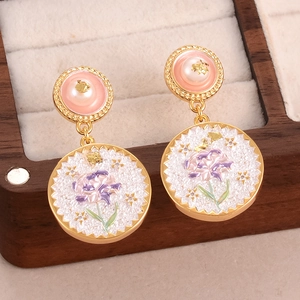 Close-up of baroque pearl flower earrings with purple enamel in a wooden jewelry box