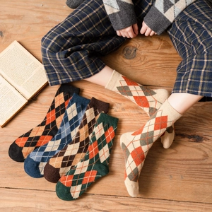 Vintage argyle pattern crew socks in five warm colors displayed on a rustic wood background