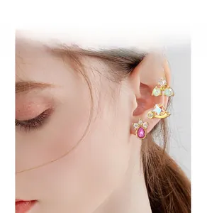 Detail view of a set of golden heart and star zircon stud earrings worn by a model