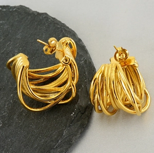 Macro shot of gold layered multi-strand earrings on natural rock and grey fabric background