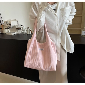 Rosa Stoff-Schultertasche mit MISS YOUIRLSEF-Label getragen von Model in Café-Szene