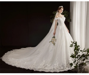 Detail of off-shoulder wedding dress with sequin fabric, long train and fringe accents