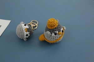 Close-up of handmade crochet penguin keychains with miniature hat and crossbody bag detail