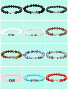 Macro view of assorted 8mm natural stone bead bracelets with engraved alloy charm details