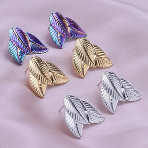 Macro detail of leaf-shaped stainless steel earrings in gold, silver, and iridescent colors