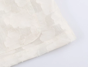 Gros plan sur le tissu du blazer beige révélant la texture jacquard à carreaux