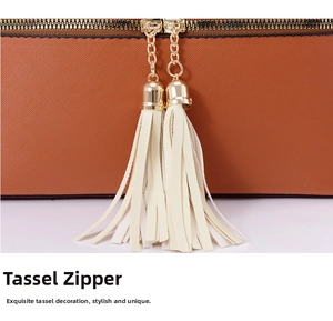 Detailed close-up of double golden zippers with off-white leather tassels on a brown bag