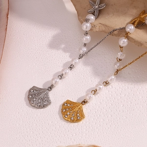 Macro shot of 18K gold and silver starfish pendants with pearls on a beach-style backdrop