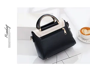 Side view of contrast black and white crossbody bag with top handle and gold hardware