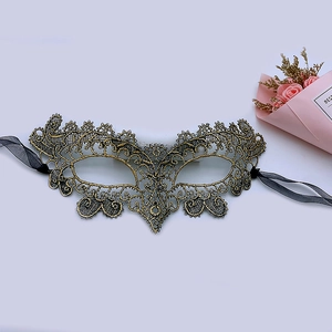 Close-up of golden lace masquerade mask with intricate hollow patterns and black satin ribbons