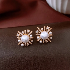 Macro detail of 18k gold-plated pearl flower earrings with sparkling cubic zirconia