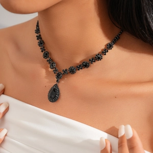 Close-up of gothic black crystal water drop necklace on model with elegant floral link detail