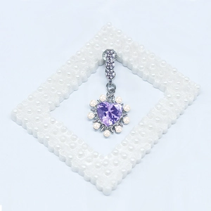 Détail du piercing de nombril avec pierre en cœur violette et perles sur fond blanc