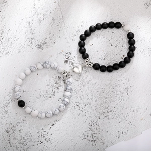 Detail of heart-shaped magnetic clasp connecting marble and black matte beaded bracelets