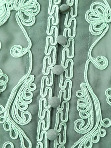 Gros plan sur une robe dos nu vert menthe avec broderie florale et boutons en tissu
