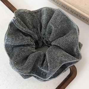 Macro shot of silver metallic pleated scrunchie showing fabric texture and shimmer
