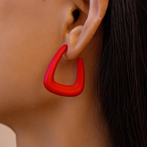 Close-up of a red matte geometric U-shaped acrylic earring worn on a female model