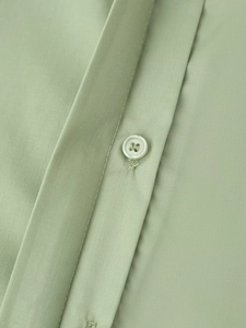 Close-up of a light green shirt showing the button detail and fine stitching texture