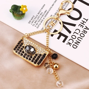 Macro view of crystal-encrusted envelope bag keychain with pearls and metallic finish