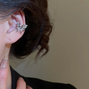 Detail of silver butterfly zircon ear cuff on ear with tassel dangles for women