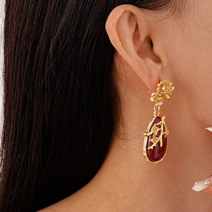 Gros plan de boucles d'oreilles fleur vintage avec pierre goutte rouge