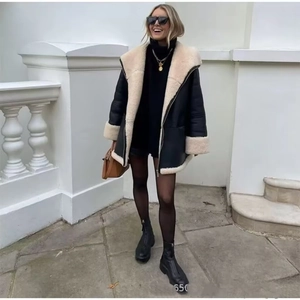 Oversized black leather jacket with beige faux shearling lining shown in outdoor street style