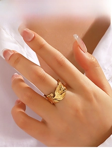 Macro detail of golden leaf ring showing intricate vein textures on a stainless steel band