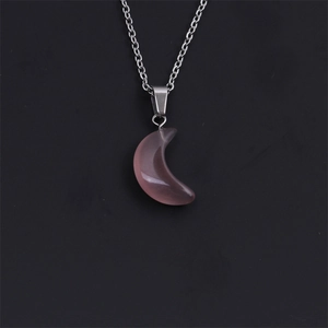 Macro shot of a pink crescent stone pendant on a silver twist chain over black background