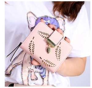 Close-up of pink faux leather wallet with hollow leaf design and gold metal pendant