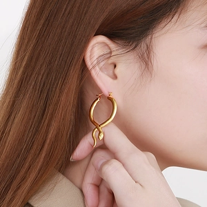 Detailed view of snake-shaped gold earrings worn for a luxurious fashion aesthetic