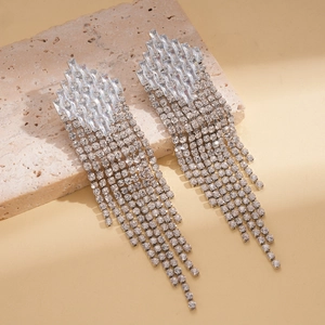 Macro detail of luxury silver tassel earrings with geometric diamonds on stone