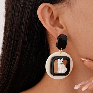 Close-up of cute cartoon puppy acrylic earrings with black and white contrast on model
