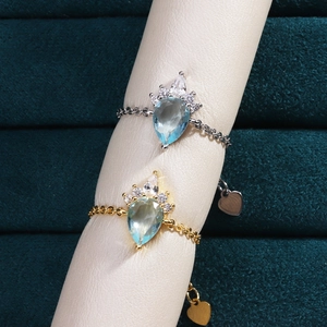 Detail of 18K gold and silver chain rings with pear-cut blue gems on velvet