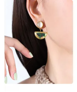 Detail of vintage gold earrings with cat eye stones and emerald green resin inlays