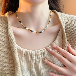 Detail of freshwater pearl necklace with multi-colored beads on a beige shirt