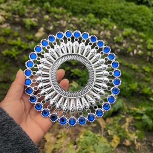 Macro shot of silver circular metal wall decor with radial pattern and blue eye stones
