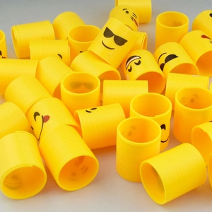Close-up of yellow mini spring toys with diverse emoji faces and black spiral details