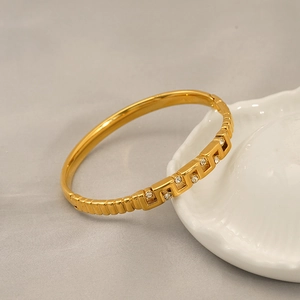 Detail of gold-plated Cuban bracelet with Greek pattern and inlaid white zircon crystals