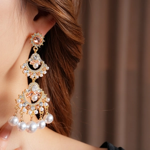 Close-up of fan-shaped pearl tassel earrings with pink gems and crystals on model