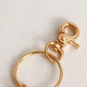 Detailed close-up of a glossy gold metal keychain with a ring and a rotating swivel clasp
