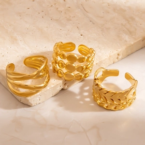 Detailed view of three adjustable gold rings with leaf and bead textures on stone surface