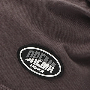 Close-up of stylish dark taupe knitted beanie featuring a 3D rubber fashion logo patch