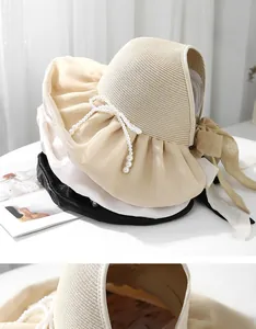 Stack of women's straw sun hats with pearl bows and elegant ribbons in multiple colors