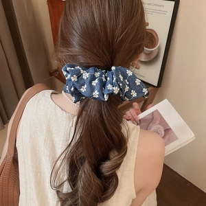 Close-up of floral denim blue scrunchie showing fabric texture and pleats on hair