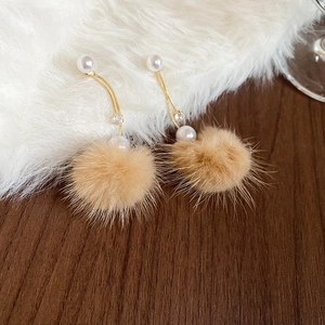 Detail of elegant gold drop earrings featuring pearls, zircon, and fluffy brown pom-poms