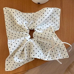 French style polka dot bow hair scrunchie in black and white on a wooden surface